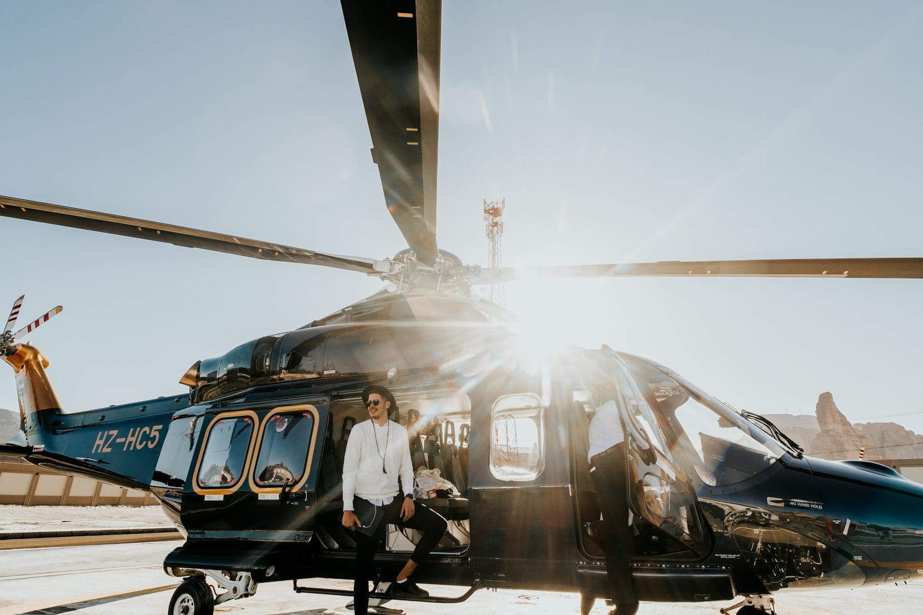 Passenger boarding a helicopter on the pad into sun flare