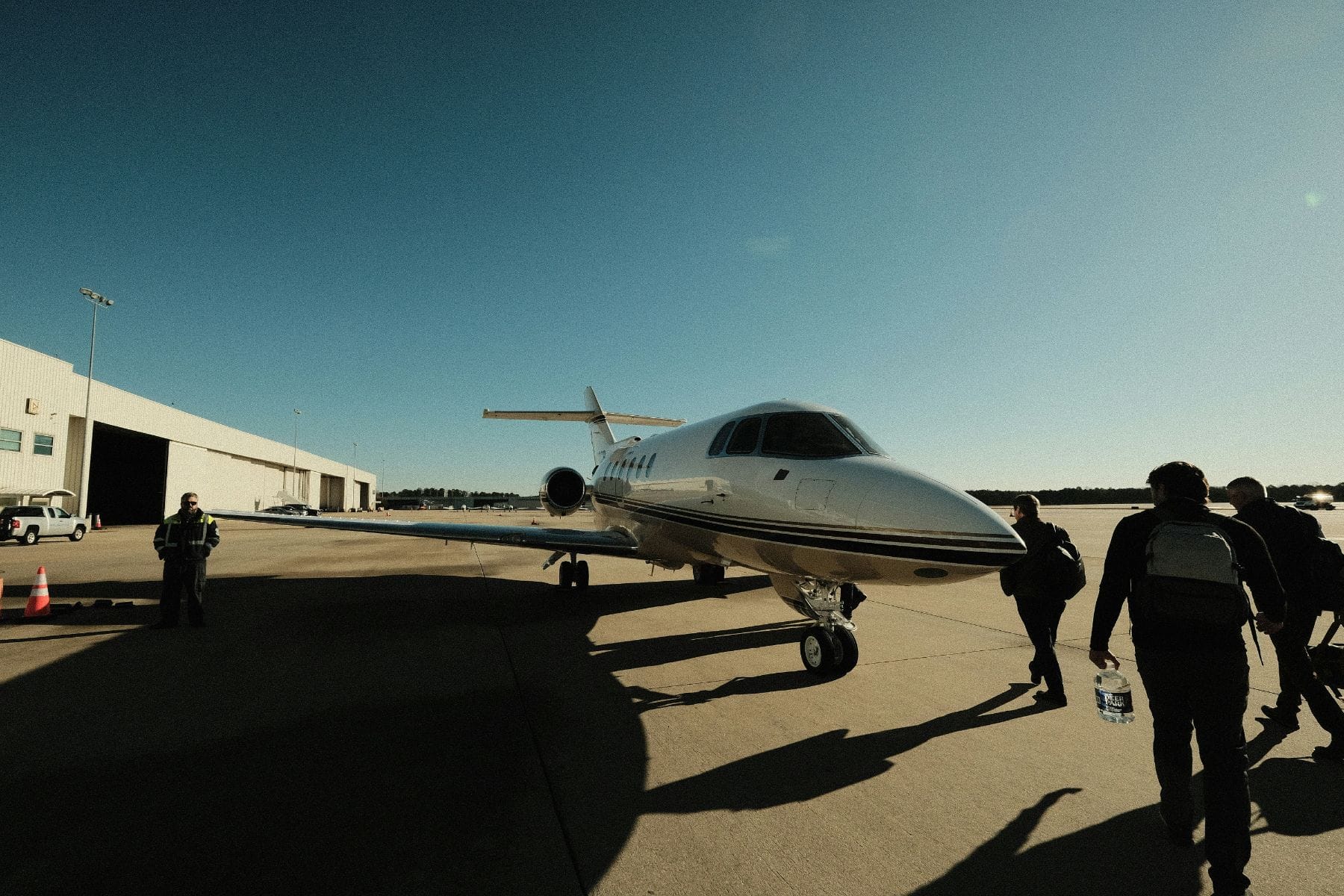 Passengers walking across the ramp toward a waiting private jet