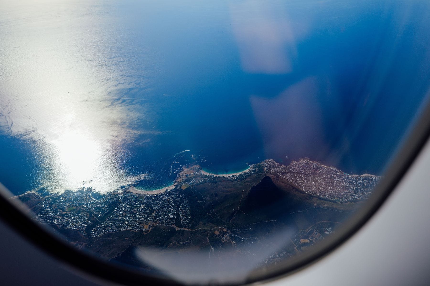 A coastline and mountain seen through an aircraft window from altitude
