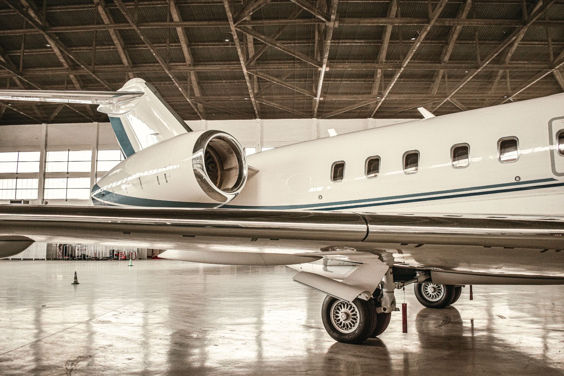 A private jet parked inside a hangar, viewed from beneath the wing