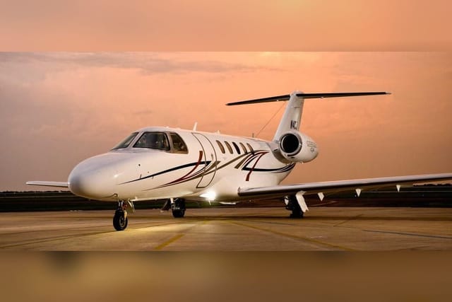 A Cessna Citation CJ4 light jet on the ramp under a pink evening sky