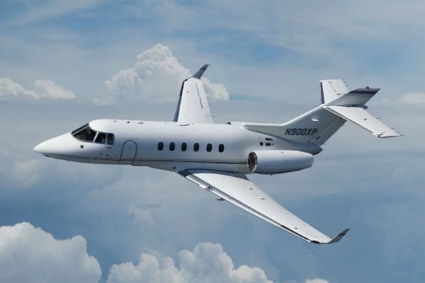 A Hawker 900XP midsize jet in flight above broken cloud